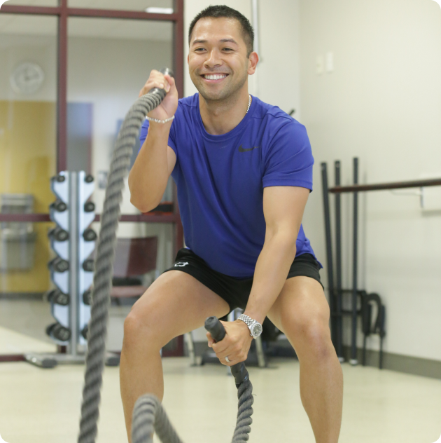 A man squatting with a rope.