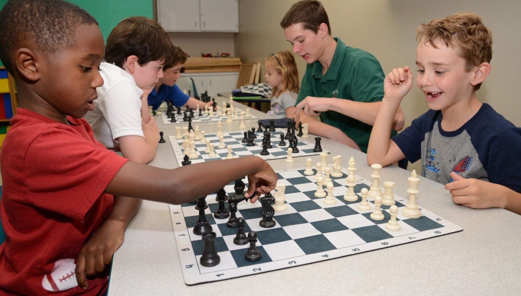 A group of children playing chess in a classroom.