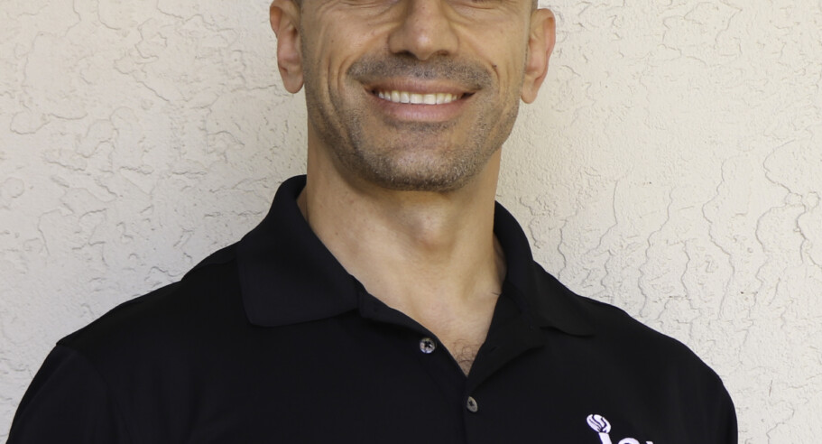 A bald man wearing a black polo shirt.