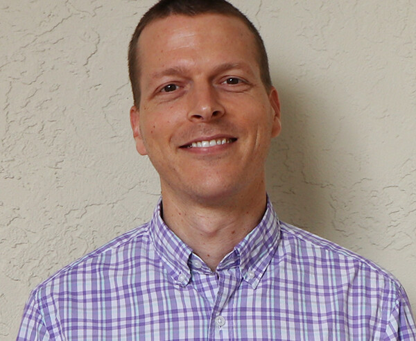 A man wearing a purple and white checkered shirt.