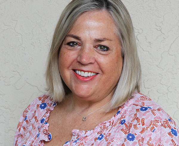 A smiling woman in a floral top.