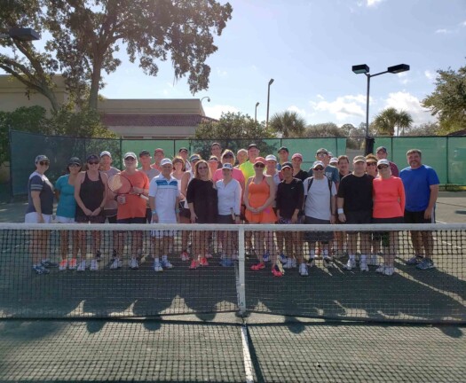 Group of adults on tennis court.