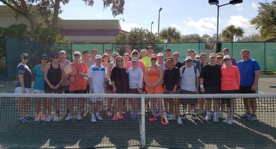 Group of adults on tennis court.