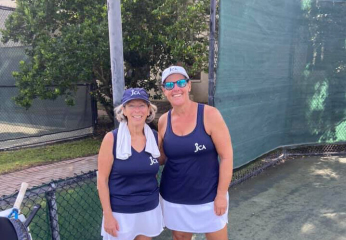 Two women smiling in tennis outfits.