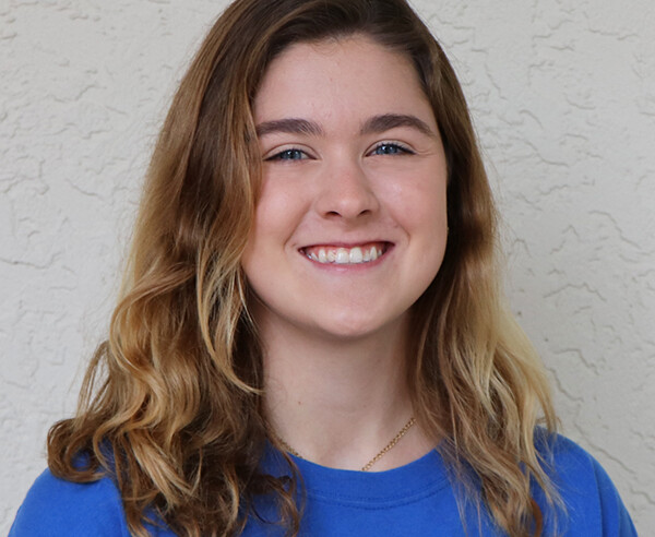 A young woman wearing a blue t - shirt.