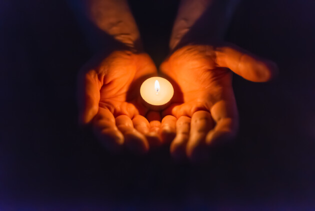 A person holding a candle in their hands.
