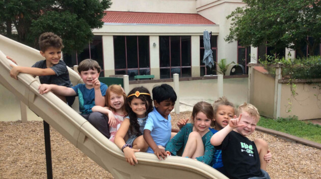 Group of kids all on the playground slide.