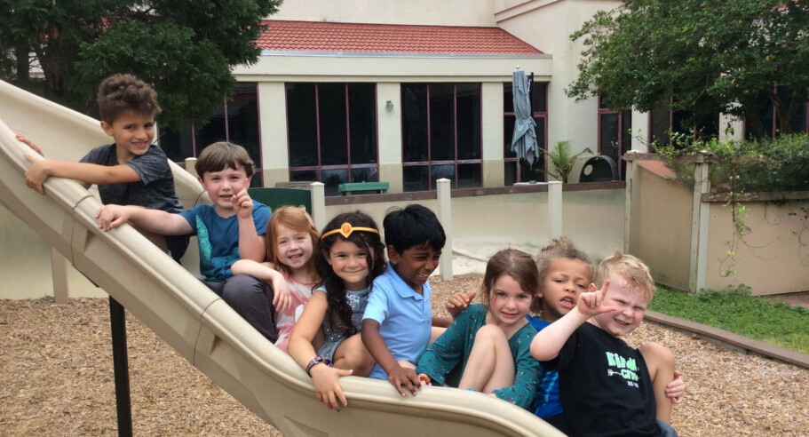 Group of kids all on the playground slide.