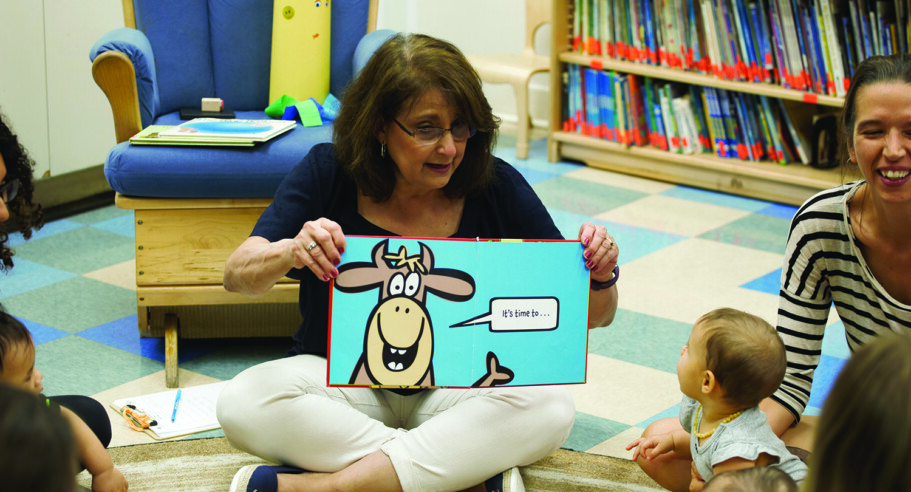 A woman reading a book to a group of children.