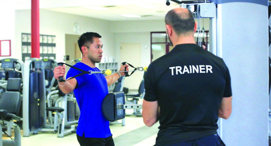 A man and a woman working out in a gym.