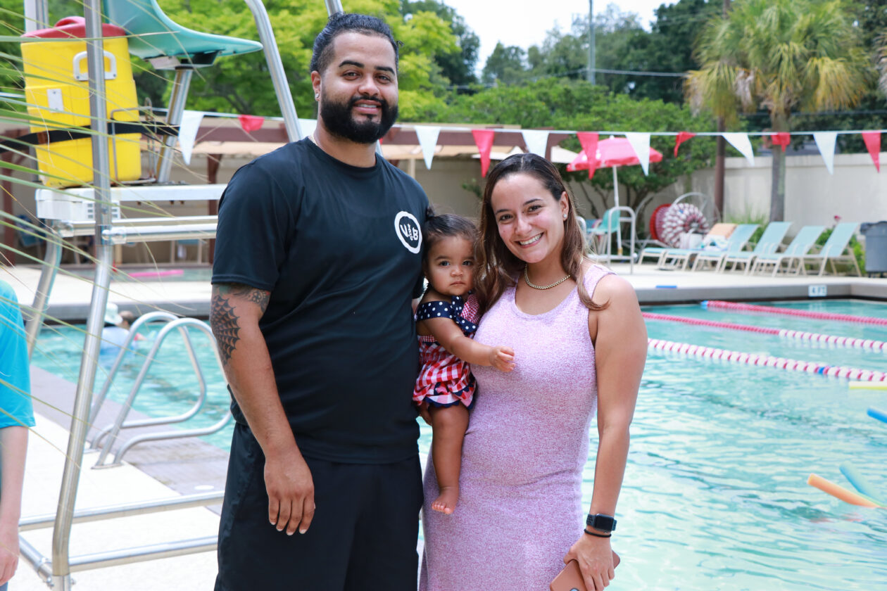 A man and woman standing next to a child in a swimming pool.