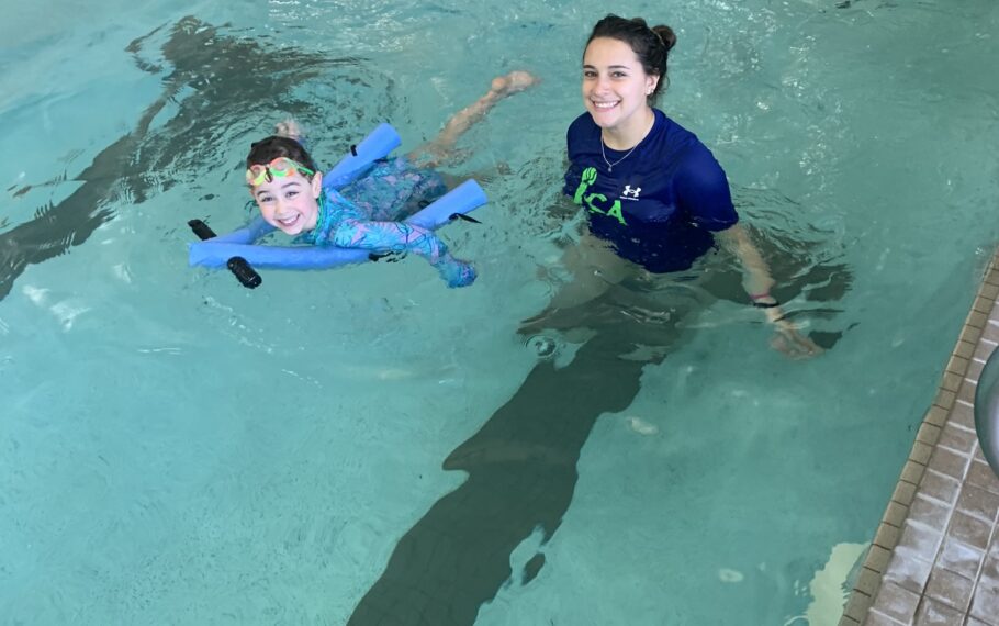 A woman and a child swimming in an indoor pool.