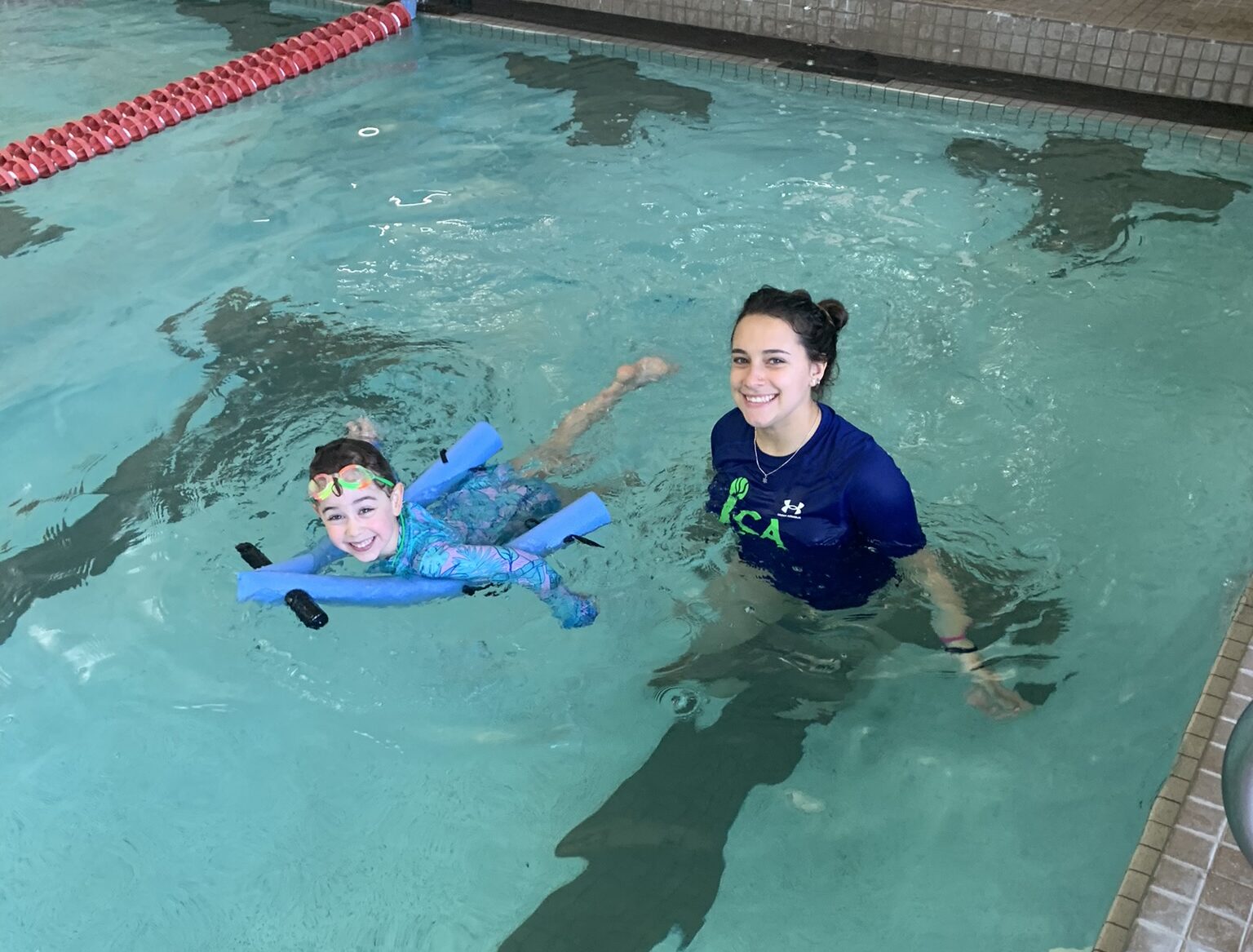 A woman and a child swimming in an indoor pool.