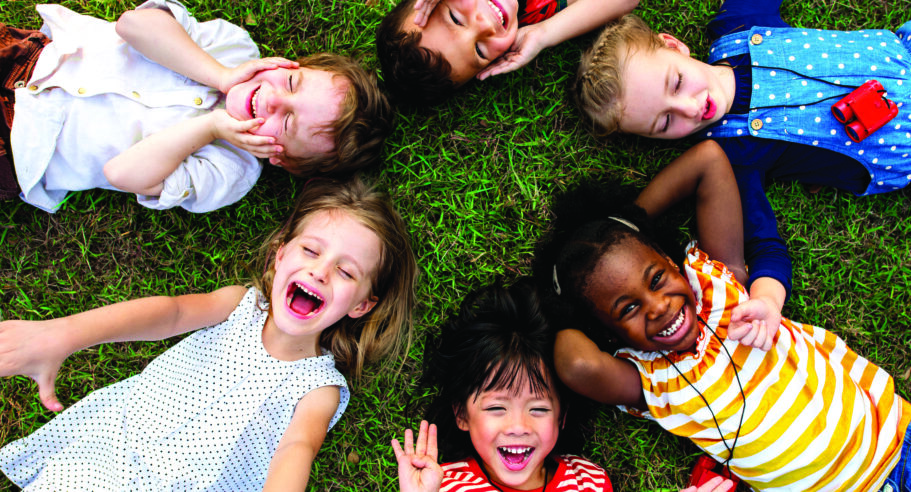 Kids laying in a circle on the grass laughing and smiling