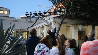 A group of people watching a menorah.