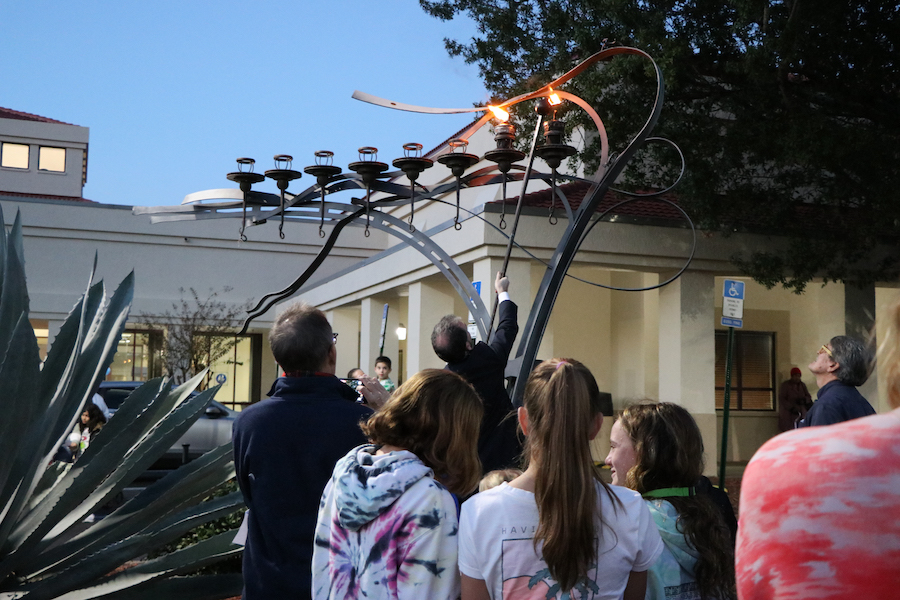 A group of people watching a menorah.