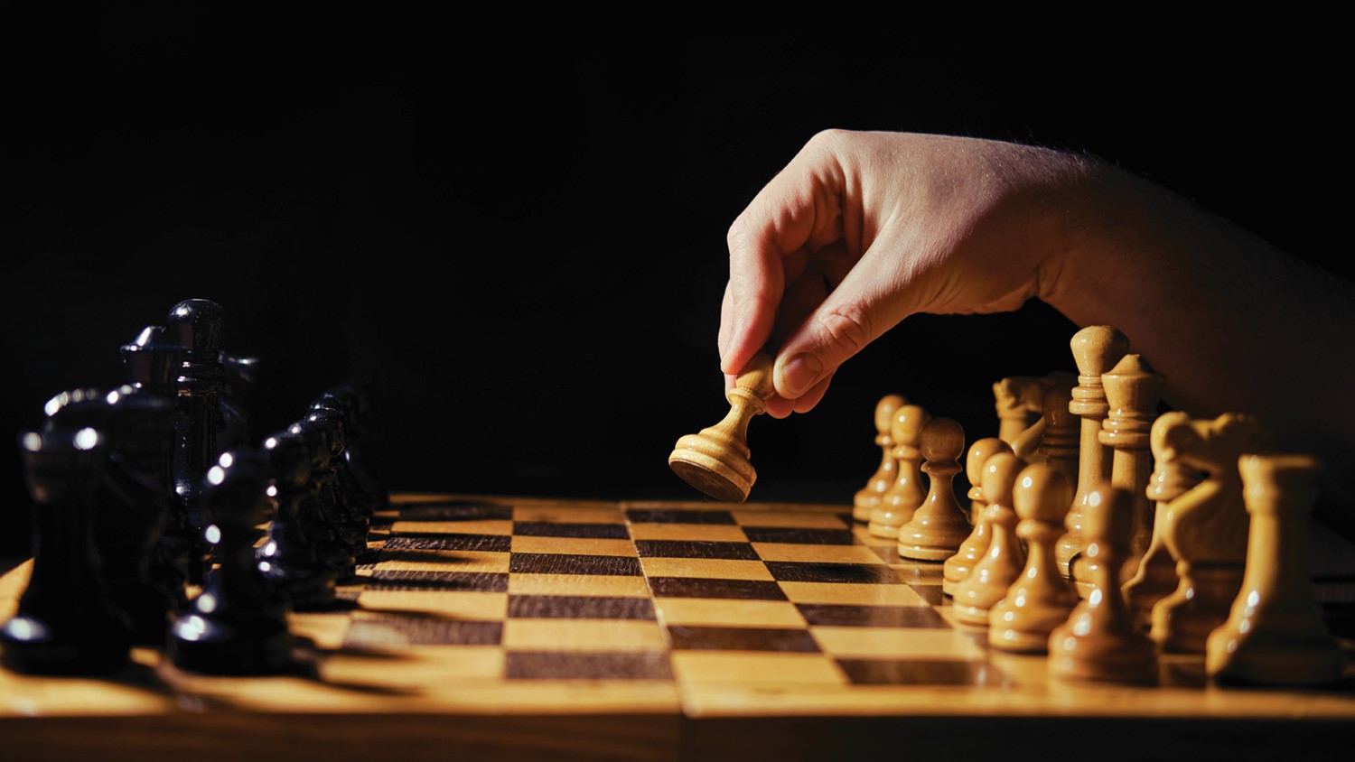 A person is putting a pawn on a chess board.