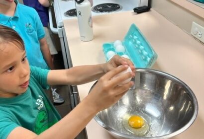 A group of children are preparing eggs in a kitchen.