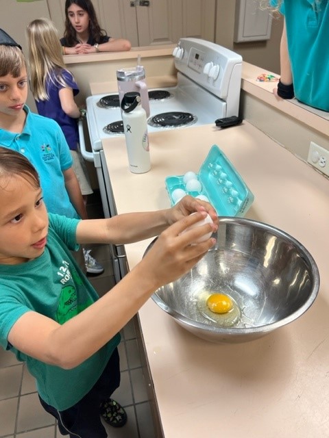 A group of children are preparing eggs in a kitchen.