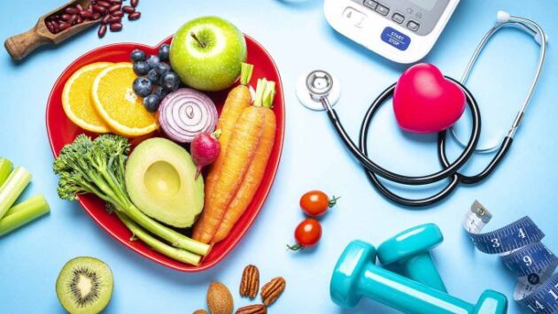 A heart shaped bowl of fruits, vegetables and a stethoscope.