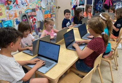 A group of children using laptops in a classroom.