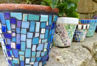 Mosaic flower pots on a stone wall.