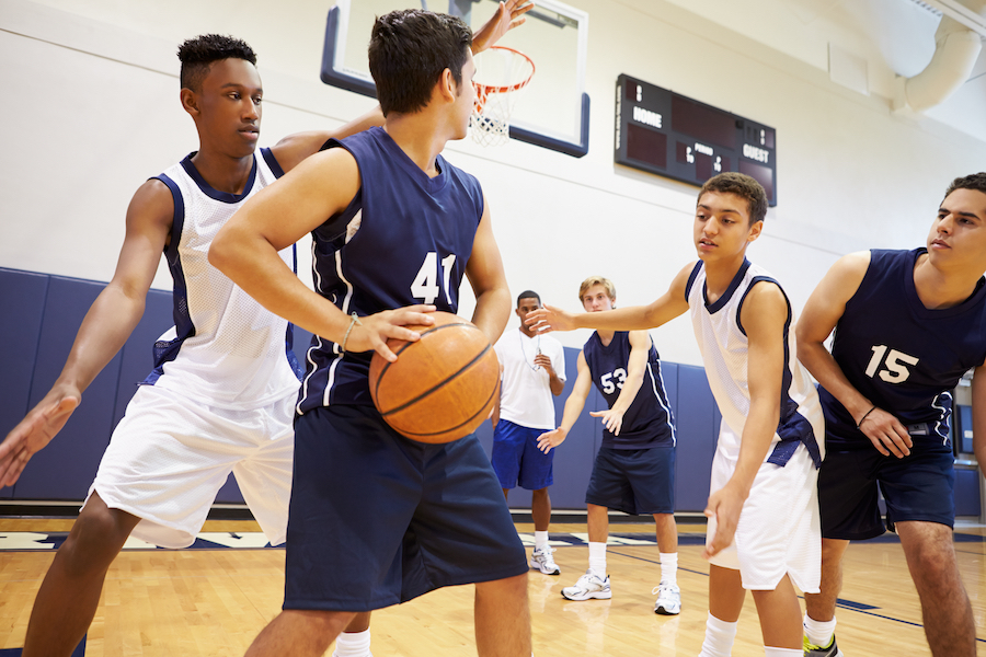 A group of young men playing basketball in a gym.