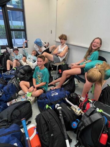 A group of people sitting on the floor with backpacks.