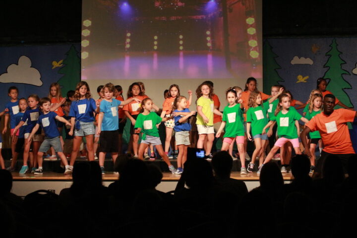 A group of children standing on stage on a stage.