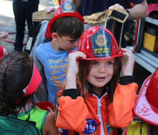 Girl smiling with fireman hat on during the Jacksonville Fire Department's visit to Camp Sabra