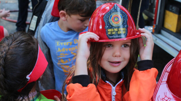 Girl smiling with fireman hat on during the Jacksonville Fire Department's visit to Camp Sabra