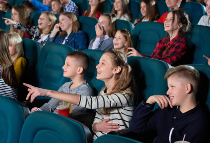 Shot of cheerful kids enjoying a movie at the cinema.