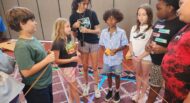 A group of children standing around a table.