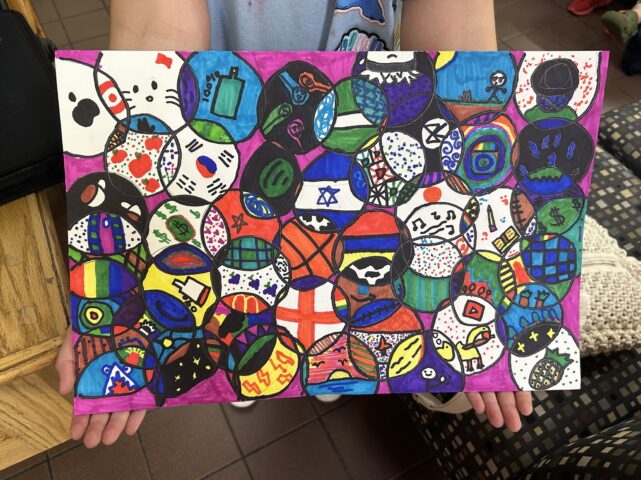 Person holding a colorful artwork featuring various flags and symbols inside circles.