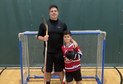 Floor hockey coach posing with young hockey player