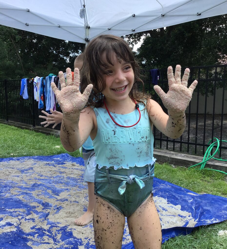 A little girl with her hands in the sand.