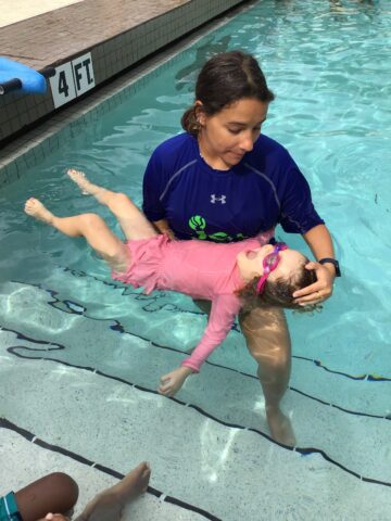 A woman holding a child in a swimming pool.