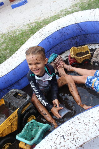Two children playing in a mud pit.