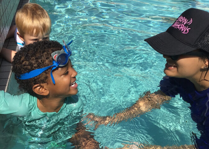 A woman in a hat and a boy in a swimming pool.