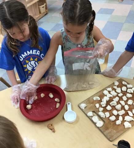 A group of children are preparing food in a classroom.