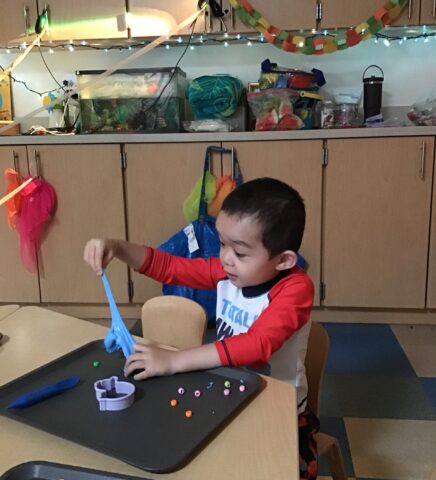 Child playing with blue slime at a table, surrounded by craft supplies and decorations.