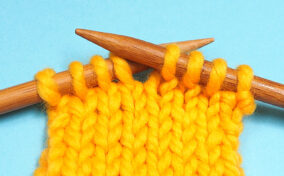 A pair of knitting needles on a blue background.