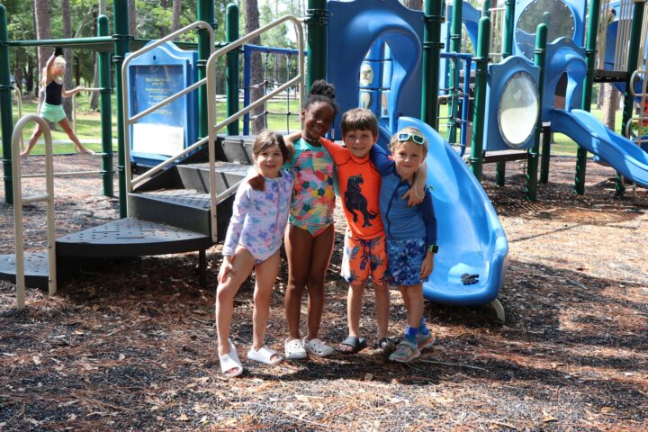 A group of children posing in front of a playground.