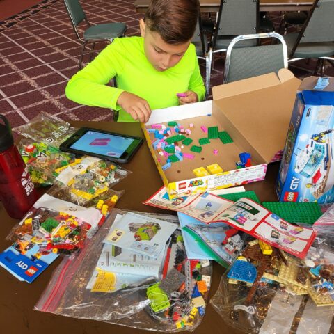A boy is sitting at a table with legos on it.