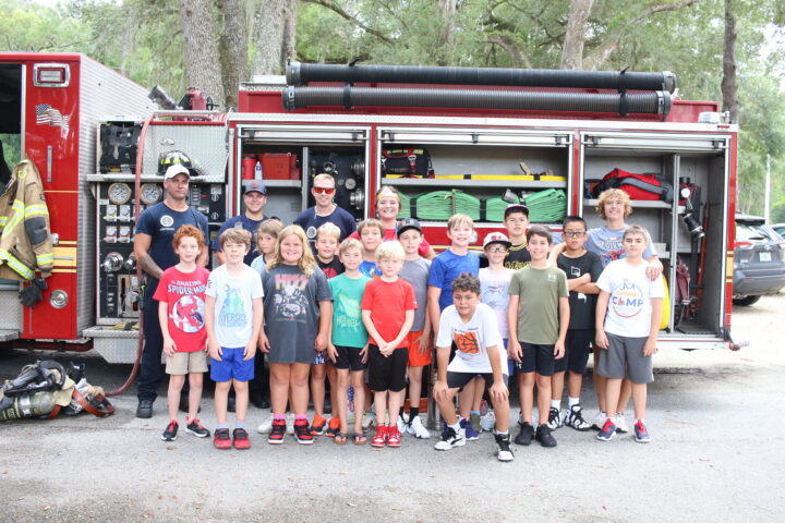 A group of kids posing in front of a fire truck.