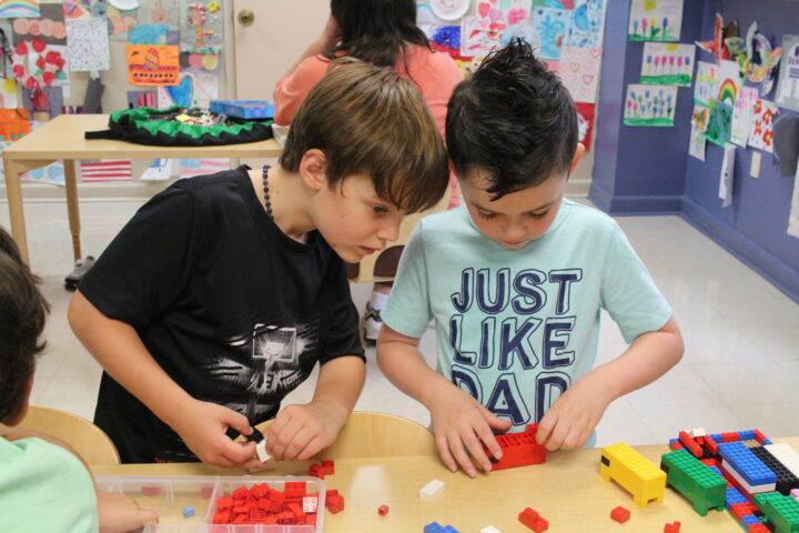 Two boys playing with legos in a classroom.