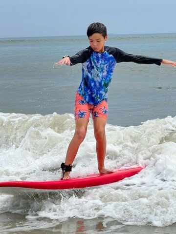 A young boy riding a surfboard in the ocean.