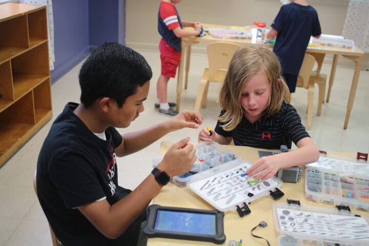 Two children working on electronics in a classroom.