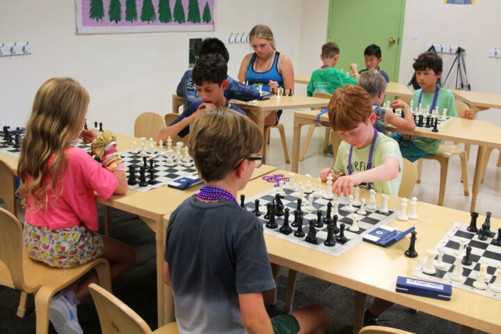 A group of children playing chess in a classroom.