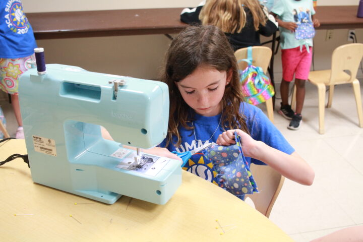 A girl using a sewing machine in a classroom.